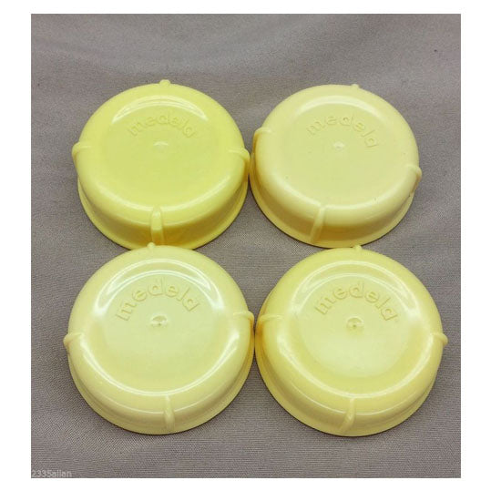 Medela yellow lids with logo on top of lids.